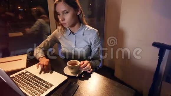 女孩在笔记本电脑上打字和喝咖啡的肖像4K视频的预览图