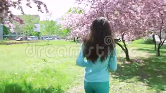 快乐的女人在春暖花开的花园里奔跑视频的预览图