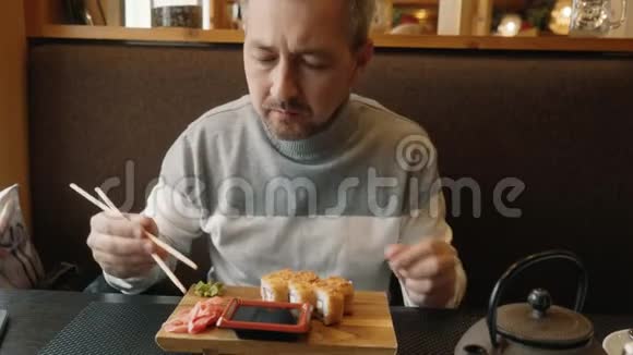 男人学会拿筷子做寿司咖啡馆里的一个男人正在吃面包卷视频的预览图
