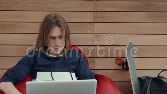 一位有创造力的男性自由职业者坐在笔记本电脑前的后视图年轻的商人在上网本工作期间视频的预览图
