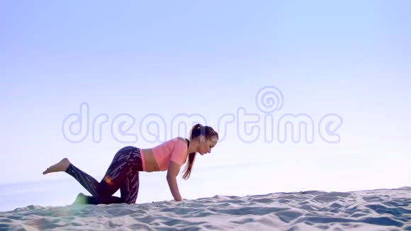 健康年轻的美女做做俯卧撑在海滩上日出时做运动来平衡和平衡视频的预览图
