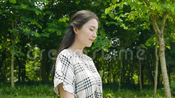 美丽的亚洲女人深呼吸微笑和享受大自然户外视频的预览图