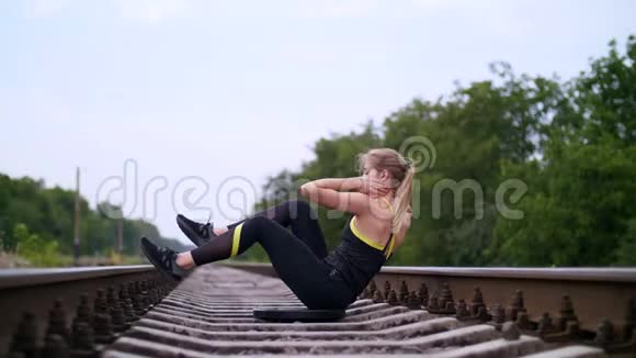 美丽的运动年轻的金发女子穿着黑色紧身裤做运动使腹部肌肉强壮视频的预览图