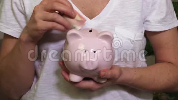 女人把钱放在储蓄罐里视频的预览图