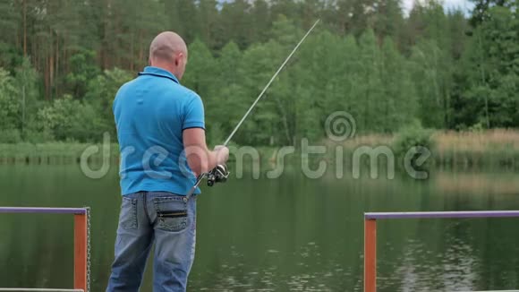 穿着蓝色T恤的人在河边钓鱼视频的预览图