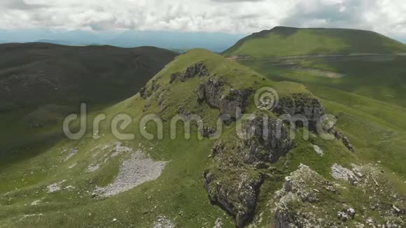 在绿色的田野间飞过一个巨大的岩层俄罗斯北高加索无人机视频视频的预览图