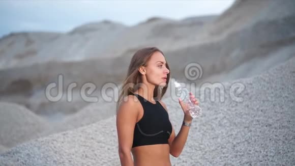 女孩在沙砾坑附近运动训练后口渴视频的预览图