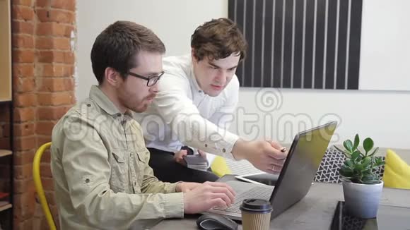 两个男人在电脑上工作坐在室内商务中心视频的预览图