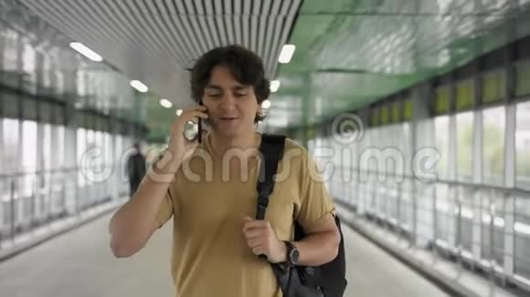 年轻男子背着背包走路在智能手机上聊天视频的预览图