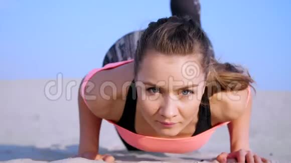 健康年轻的美女做做俯卧撑在海滩上日出时做运动来平衡和平衡视频的预览图