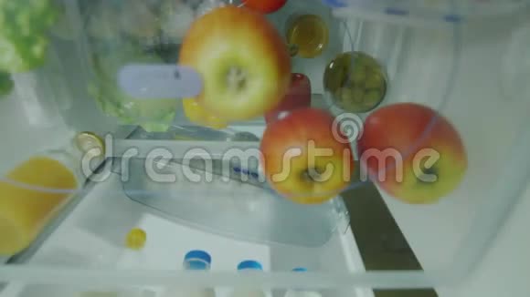 简单的水果小吃一个饥饿的女人打开冰箱拿一个苹果吃从冰箱内观看视频的预览图