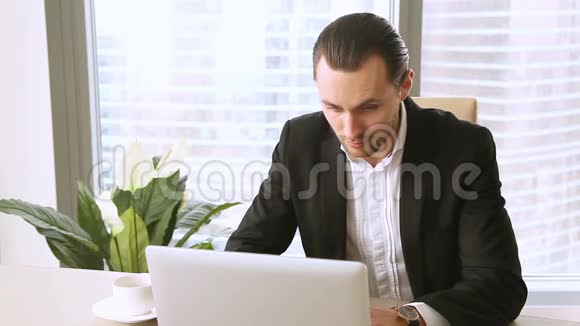 忙碌的经理在处理完手提电脑后在办公桌上打坐视频的预览图