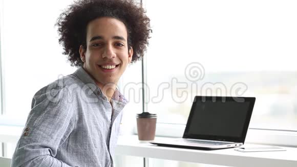 年轻微笑男子在笔记本电脑上工作的录像视频的预览图