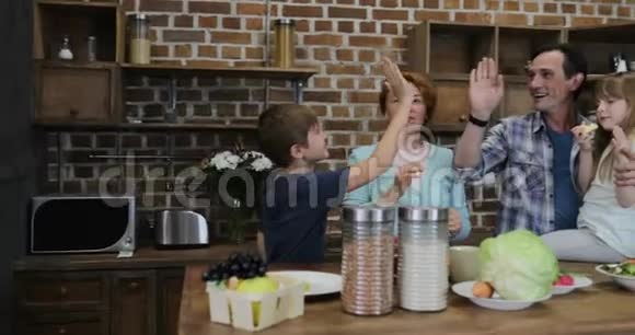 幸福的家庭等待在厨房准备食物快乐的父母和孩子在家做饭后高五视频的预览图