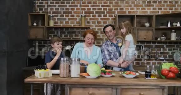 幸福的家庭帮助母亲一起做饭父母带着小儿子和女儿准备食物视频的预览图