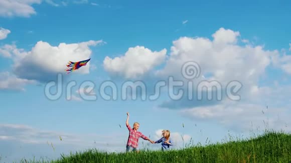 妈妈和女儿正在玩风筝沿着一座绿色的大山坡奔跑视频的预览图