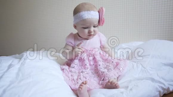 穿着粉红色裙子的小女孩坐在卧室的床上视频的预览图