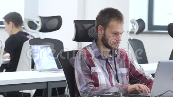 男人在办公室里用笔记本电脑工作视频的预览图