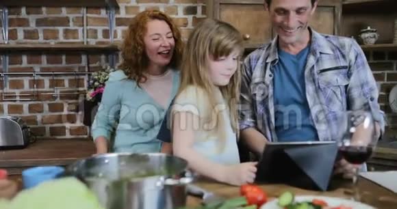 厨房数字餐桌上的快乐家庭观察视频有两个孩子在家聊天的父母视频的预览图