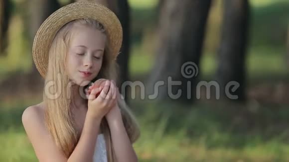 在户外吃美味桃子的少女微笑视频的预览图