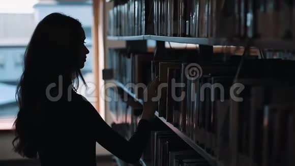 图书馆书架前一个女孩看书的剪影视频的预览图