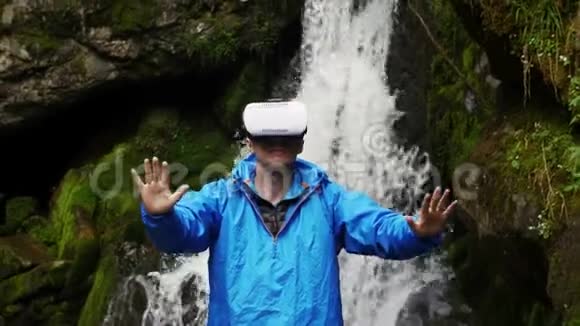 一个人在山瀑布的背景上使用虚拟现实眼镜视频的预览图