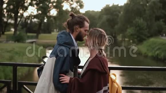 年轻的幸福夫妇在日落时和河一起散步美男美女抱桥上谈视频的预览图