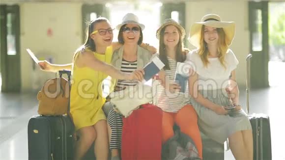 四名携带大型旅行箱的女旅客坐在机场候机室里面有护照和机票视频的预览图