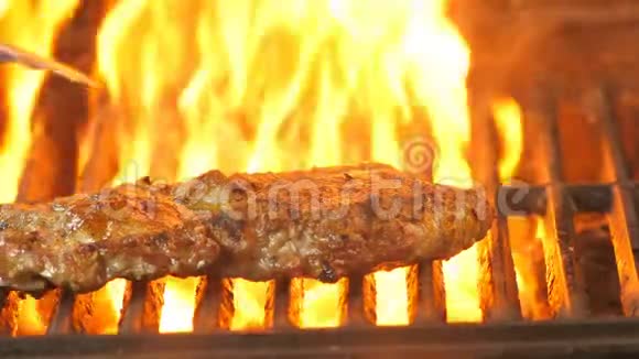 一块多汁的牛排放在烤架上厨师用钳子把它翻过来背景是一种火焰一种宏光视频的预览图