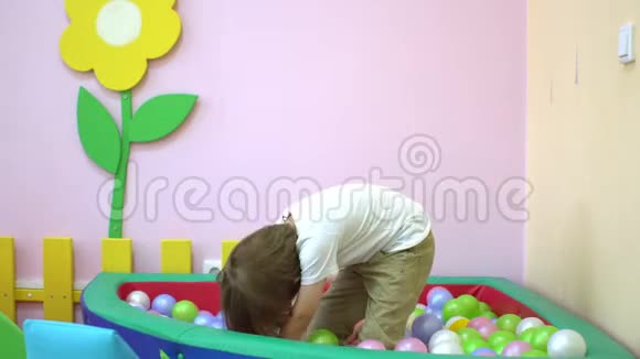 可爱的白种人小男孩和小女孩在多种颜色的球池中玩耍学前教育视频的预览图