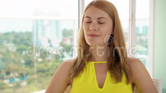坐在阳台上戴太阳镜的年轻女人的肖像公园和城市景观视频的预览图