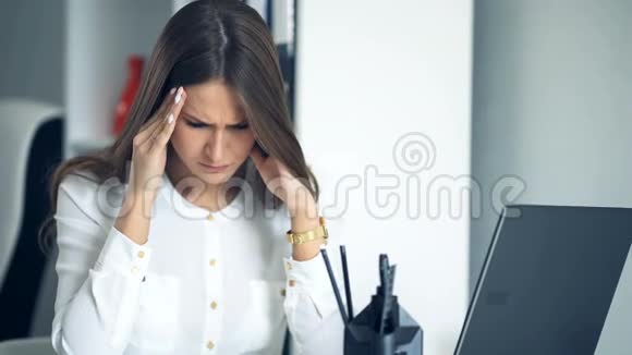 在办公室工作的疲惫的商务女性双手捧着她的头视频的预览图