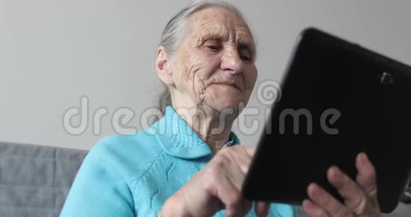 奶奶用皱纹的手拿着一块电子平板电脑视频的预览图