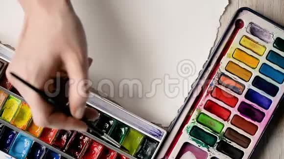 艺术家用水彩颜料在一张纸上作画手拿刷子在框架里视频的预览图