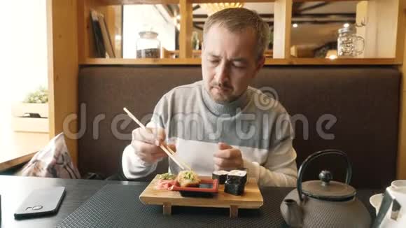 男人学会拿筷子做寿司咖啡馆里的一个男人正在吃面包卷视频的预览图