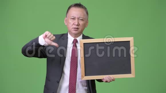 成熟的日本商人绿色背景下拿着黑板视频的预览图