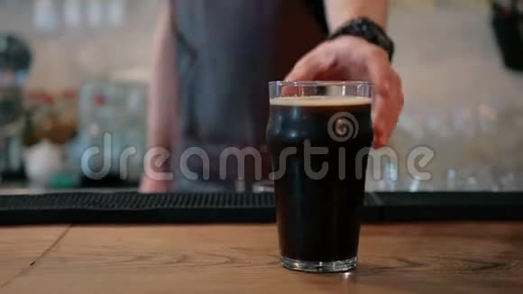 酒保把一杯黑啤酒放在酒吧里视频的预览图