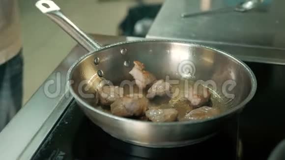 厨师把肉放入煎锅中炸并在餐厅厨房中加入酱汁视频的预览图