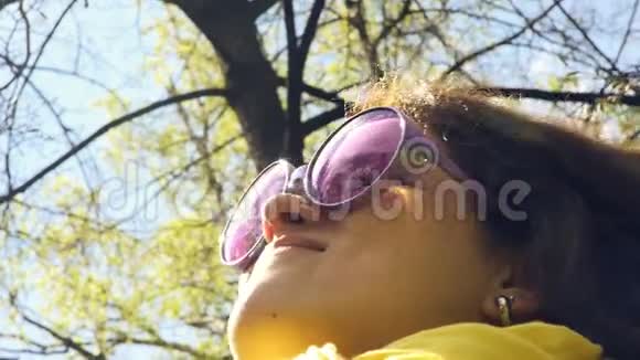 春天森林背景下一位带雀斑和粉红色眼镜的快乐年轻女子的肖像视频的预览图
