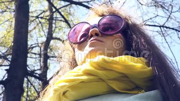 春天森林背景下一位带雀斑和粉红色眼镜的快乐年轻女子的肖像视频的预览图