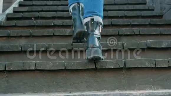 腿女人穿着蓝色牛仔裤和黑色靴子爬木楼梯视频的预览图