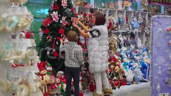 欢乐的母子在购物中心装饰圣诞树的全长后景视频的预览图