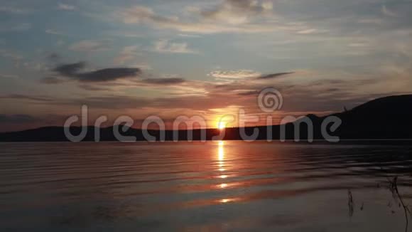 美丽的夏天日落在一个山湖上红日落山波浪向岸上奔流视频的预览图