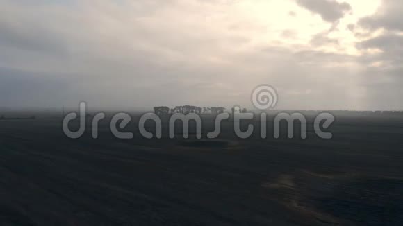 无人机在黑焦的田野上移动淡淡的薄雾远处生长着树木视频的预览图