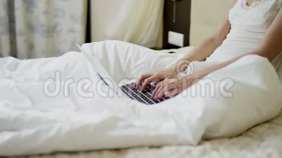 漂亮的女人在床上用手提电脑键盘打字视频的预览图