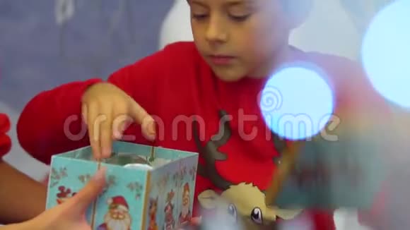 小男孩打开圣诞礼物的特写肖像收到雪球高兴地玩着它视频的预览图
