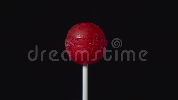 塑料棒上的棒棒糖旋转作为黑色背景上的球的形式视频的预览图