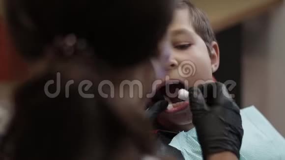 牙科医生的小男孩张开嘴坐在椅子上视频的预览图
