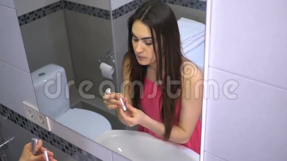 漂亮的黑发女孩在浴室用口红化妆视频的预览图