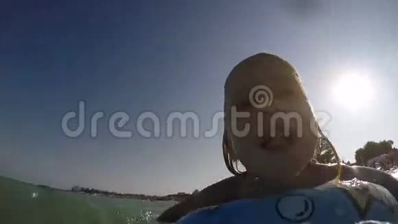 一个金发碧眼的小女孩在水里玩着一个蓝色的游泳圈视频视频的预览图